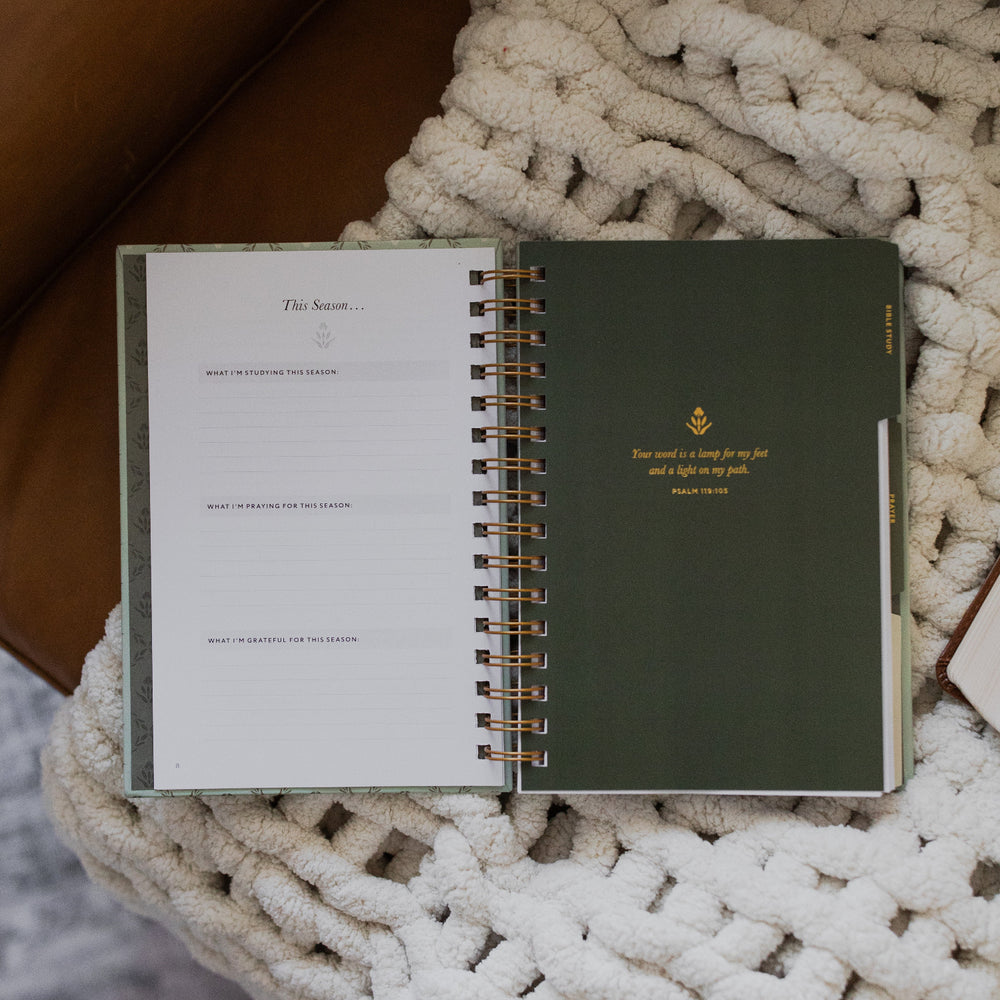 Abide Journal Refresh opened to the bible study section on a white knitted blanket on a leather couch