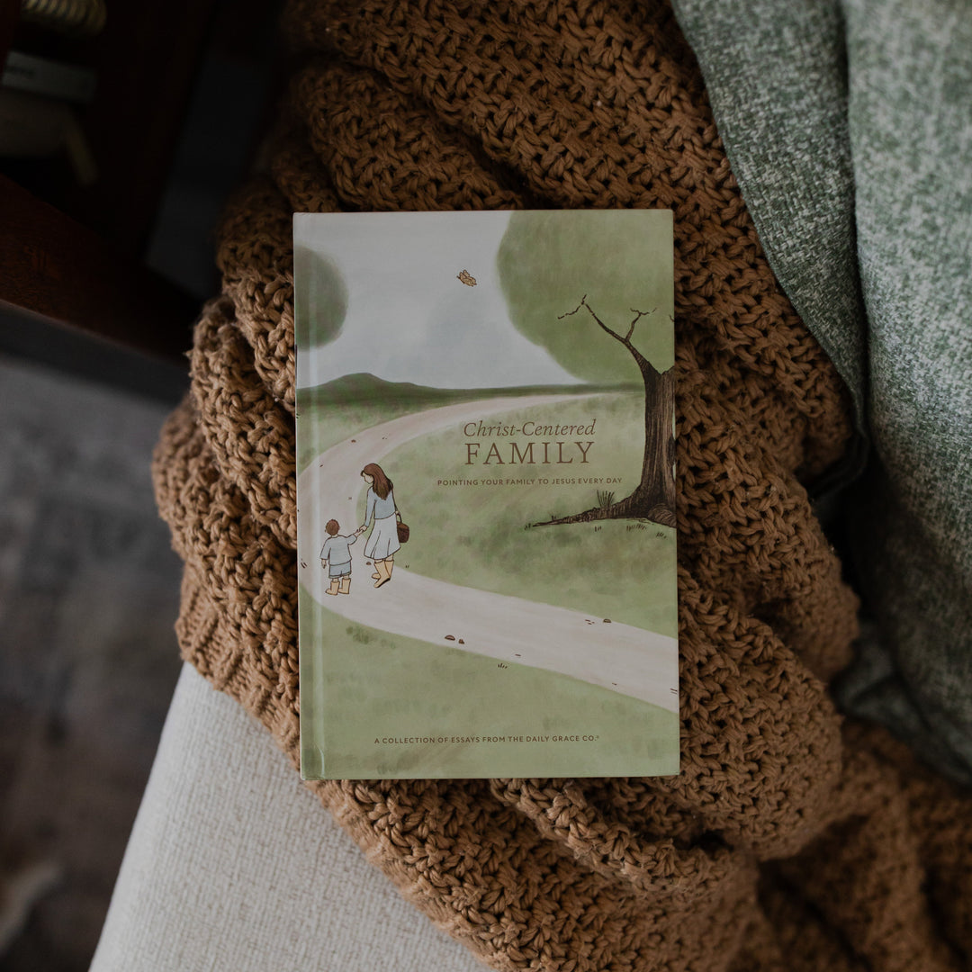 Christ Centered Family Book Cover on a brown knitted blanket resting on the arm of a creme colored couch