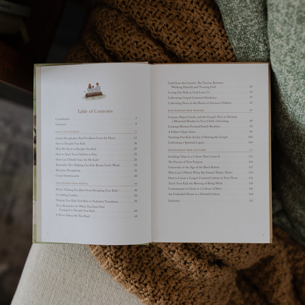 Christ Centered Family Book Opened to the Table of Contents Page laying on a brown knitted blanket resting on a creme colored couch