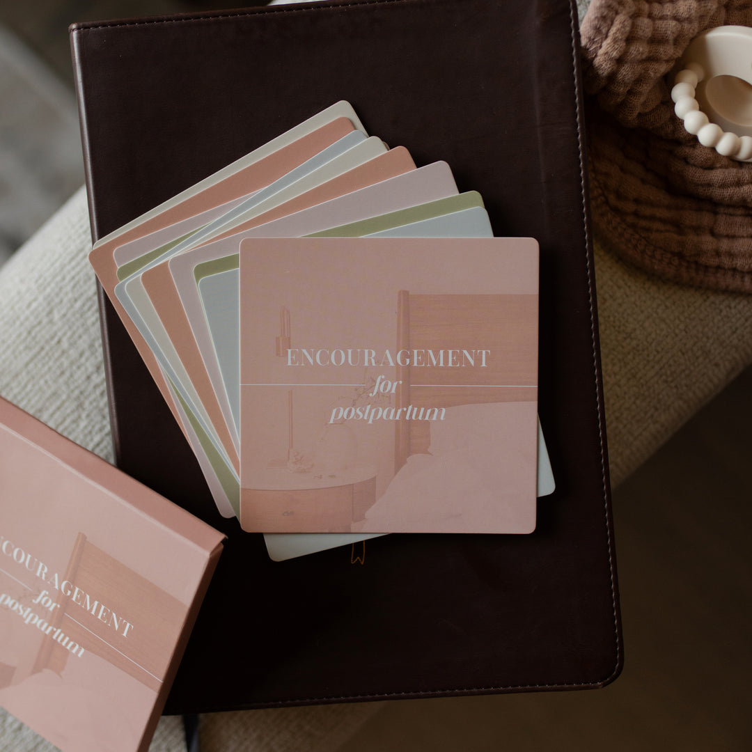 Stack of cards with 'Encouragement for postpartum' text on a dark surface.