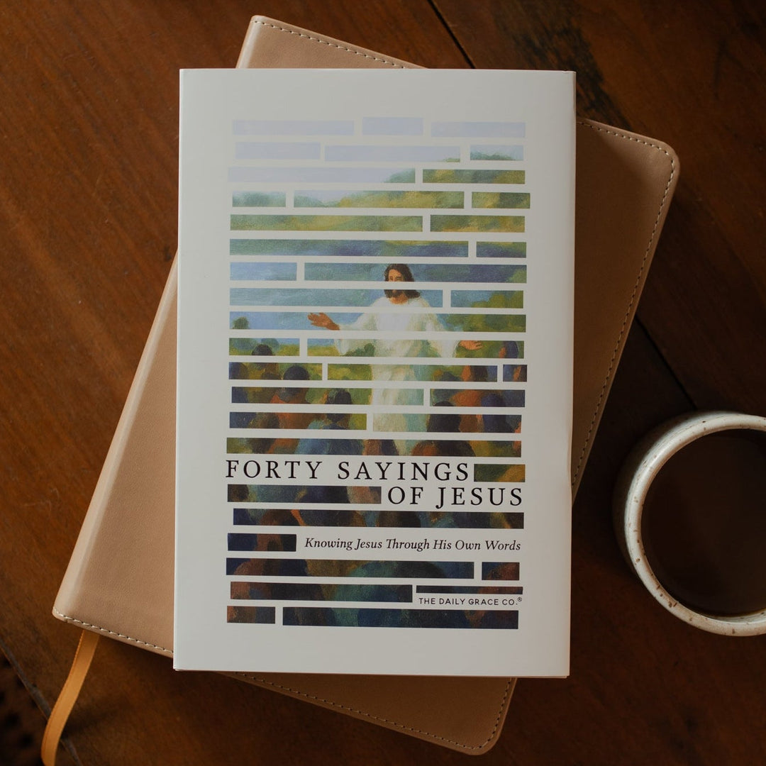 Forty Sayings of Jesus hardcover cover on a closed bible near a coffee cup on a wooden table