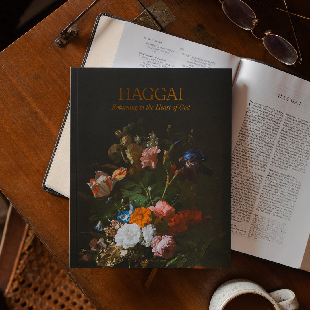 Haggai study cover on an open bible on a wooden desk near a coffee cup and a pair of eyeglasses