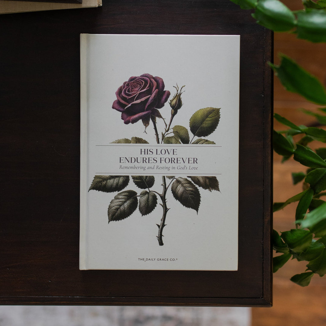 His Love Endures Forever book cover on a dark wooden table with some greenery nearby