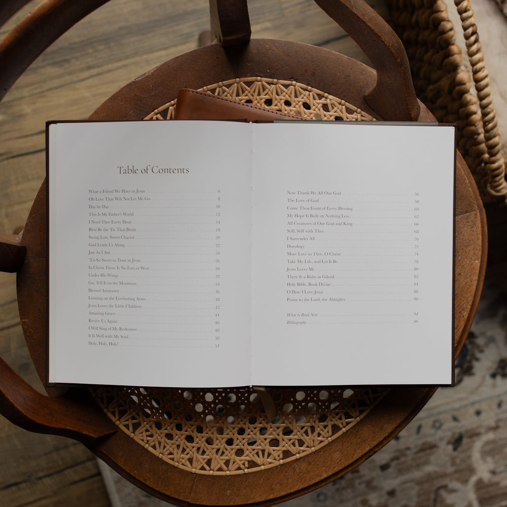 The I need Thee Every Hour book opened to the table of contents page on a wicker chair