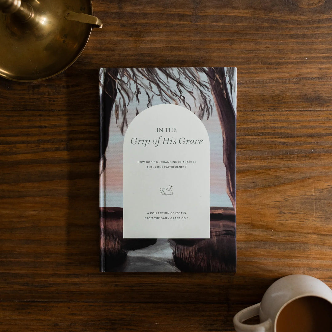 In the Grips of His Grace Study Cover on a brown wooden table next to a bronze oil lamp and a white coffee cup