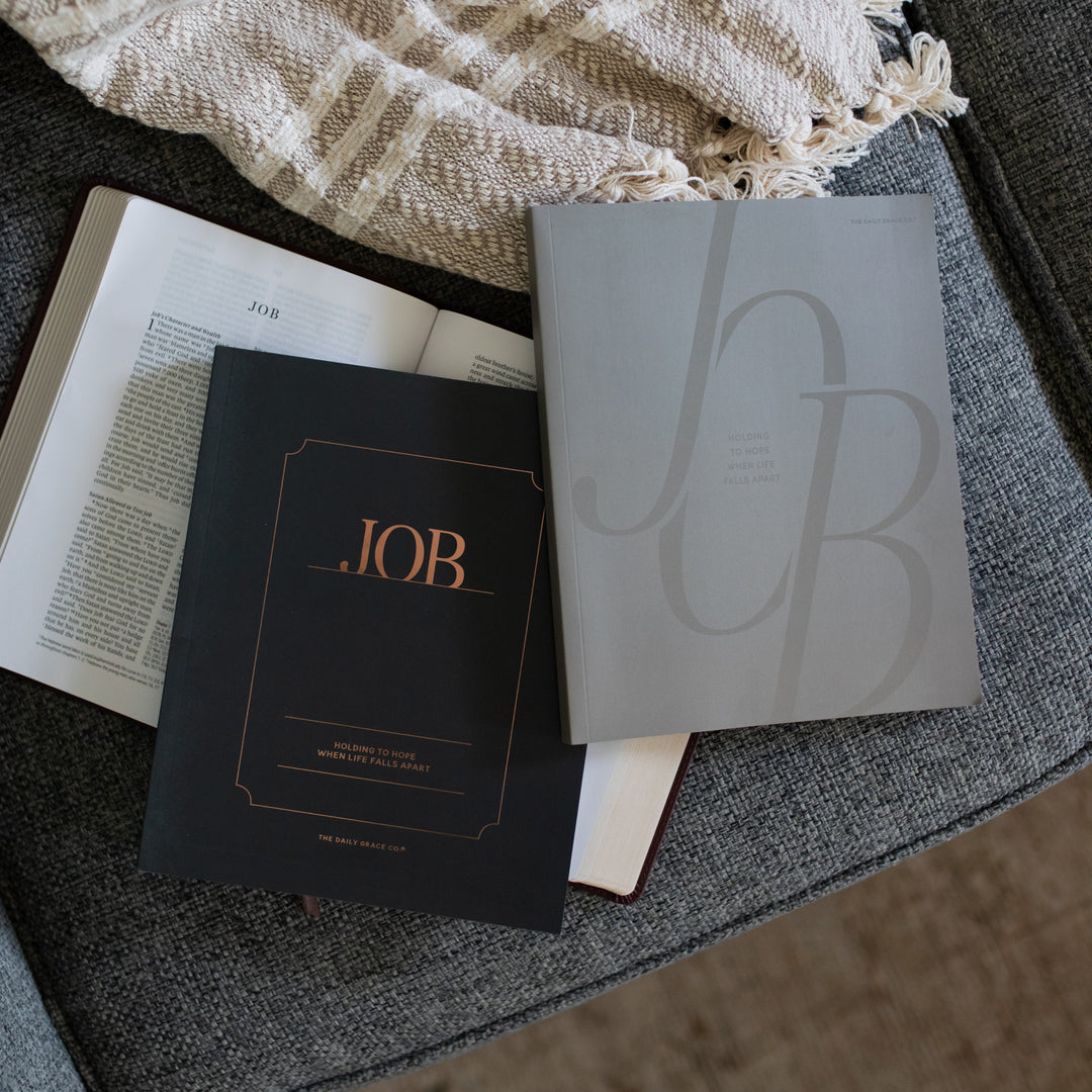 The Job Study Women's and Men's version cover on an open bible on a gray couch