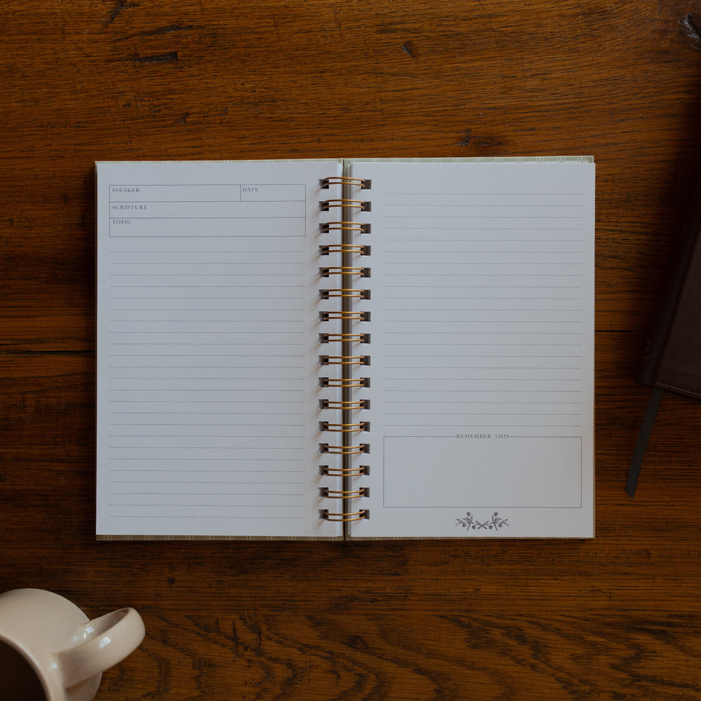 The Sermon Notes Journal with Pale Stripes opened to a blank page next to a bible and a coffee cup on a wooden table