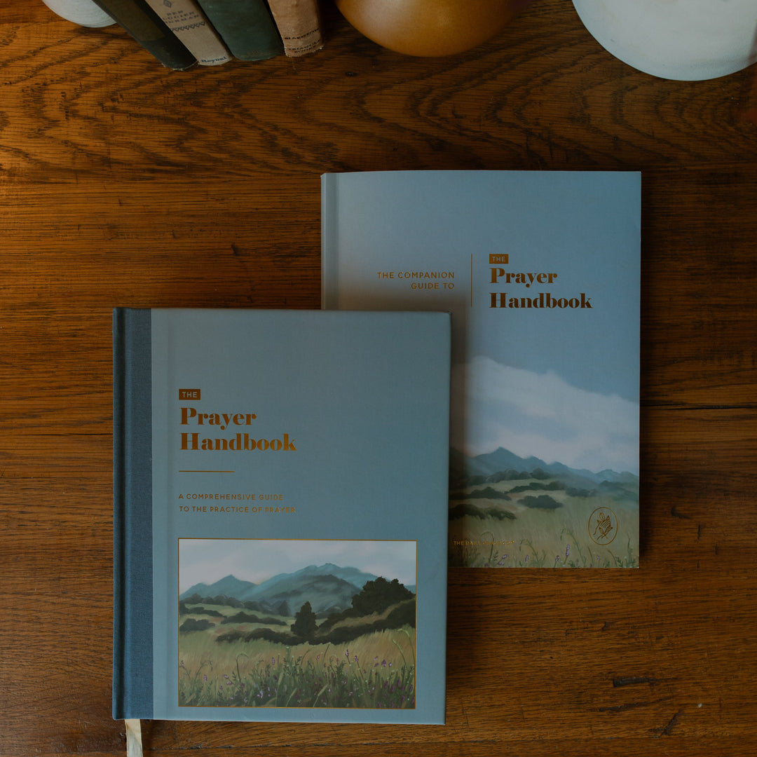 The Prayer Handbook and the Companion Guide to the Prayer Handbook covers on a wooden table