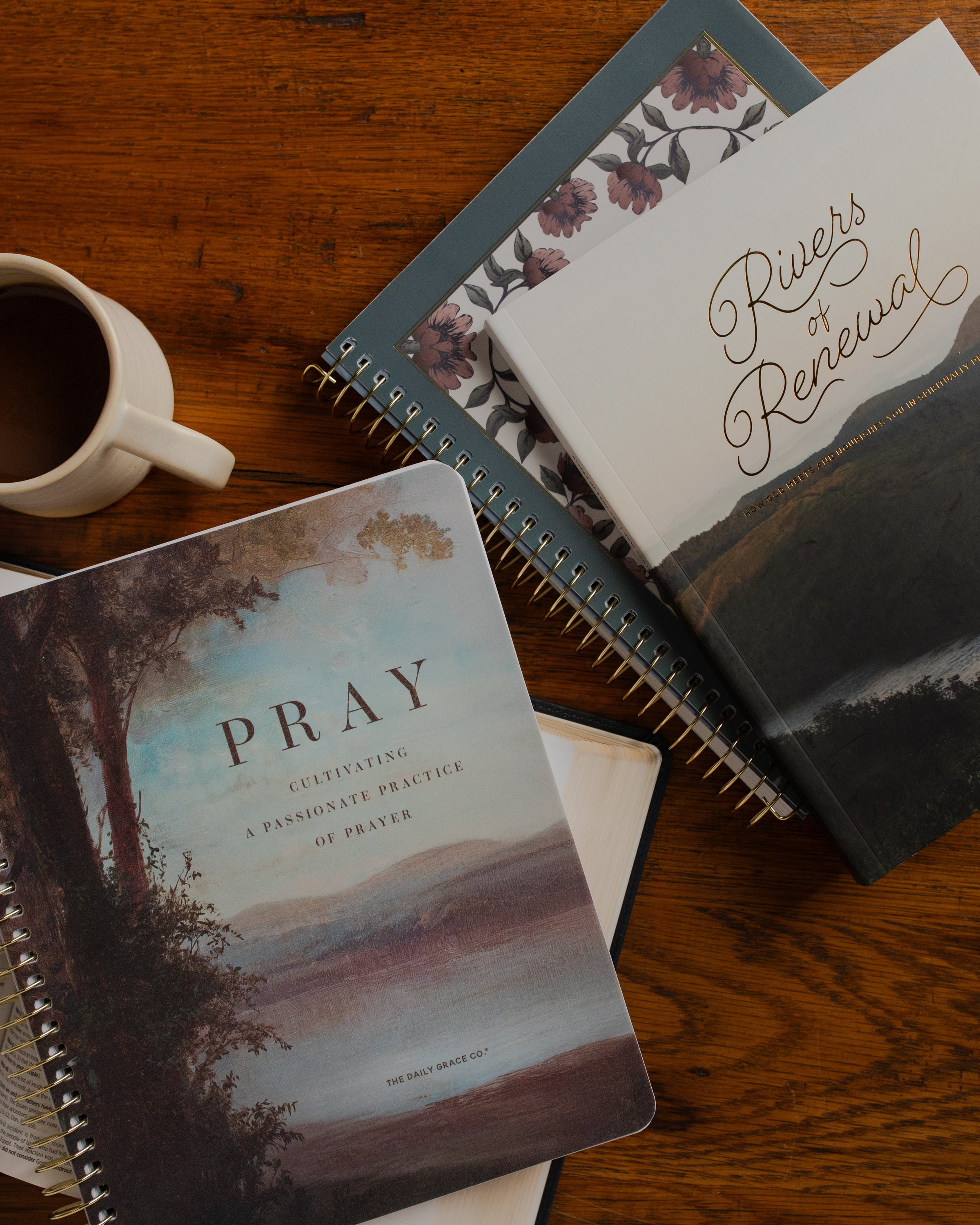 Multiple Daily Grace studies stacked on one another near multiple pens and a coffee cup