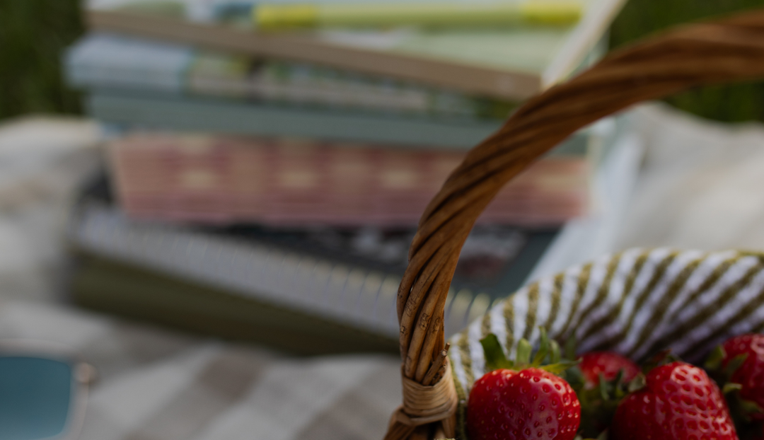 A basket of strawberries near a stack of studies